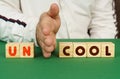 A man separates the cubes with the inscription - UNCOOL or COOL