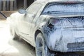 A man serves his car on a sink, applies an active foam Royalty Free Stock Photo