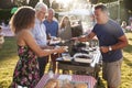 Man Serving On Barbeque Stall At Summer Garden Fete