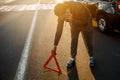 A man sets up a road triangle and calls the police, or a car service. Traffic accident