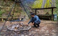 A man setting fire for barbecue in a forest against barn or hut, hike, camping or trekking adventure in the woods concept Royalty Free Stock Photo