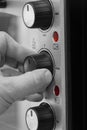 Man setting the power setting on an electric oven grill by turning a dial.