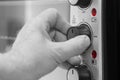 Man setting the power setting on an electric oven grill by turning a dial.