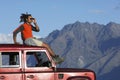 Man Shading Eyes On Top Of Jeep Near Mountains