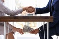 Man shaking woman`s hand and giving bribe money under table Royalty Free Stock Photo