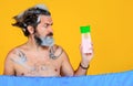Man with shampoo bottle. Bearded male washing hair. Bath time. Guy with foam on head. Copy space.