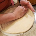 Man shapes pizza dough crust with fingers on home granite countertop