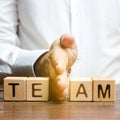 A man shares with his hand cubes with the inscription team. Dividing the collective into two parts or disbanding the team.