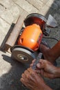 A man is sharpening iron using an orange-colored grinding machine Royalty Free Stock Photo