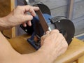 A man sharpens a knife on a grinding wheel