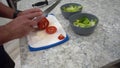 Man sharping knife and cutting a tomato for a salad. 4K