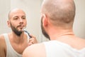 A man shaves in front of the mirrors in the bathroom. The young man tidies himself up. Portrait of a guy settles in the mirror. Royalty Free Stock Photo