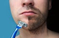 A man shaves his face without cream or foam, experiencing pain and suffering. Half face shaved half overgrown with a thick beard