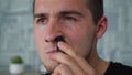 A man shaves his nose hair with a special trimer