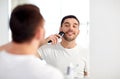 Man shaving beard with trimmer at bathroom Royalty Free Stock Photo