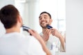 Man shaving beard with trimmer at bathroom Royalty Free Stock Photo