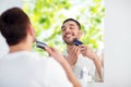Man shaving beard with trimmer at bathroom Royalty Free Stock Photo