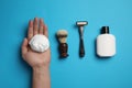 Man with shaving foam, brush, razor and bottle on light blue background, top view Royalty Free Stock Photo