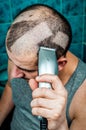 Man shaving himself with an electric razor clipper Royalty Free Stock Photo