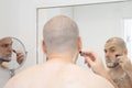 Man shaving his stubble with shaving foam and a razor in the morning in front of the mirror in the bathroom Royalty Free Stock Photo