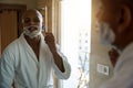 Man shaving with razor and looking at himself in mirror in bathroom Royalty Free Stock Photo