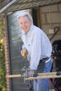 Man at shed sawing wood and smiling Royalty Free Stock Photo