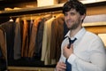 Man in a shirt gets dressed and adjusts a blue tie around his neck in the dressing room Royalty Free Stock Photo