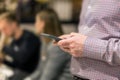 Man in shirt holding smartphone in hand. Businesman using phone during corporate meeting