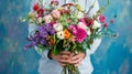 A man in a shirt holds a bright bouquet of mixed flowers on a blue background. Royalty Free Stock Photo