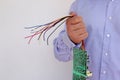 Man in a shirt holds a torn computer board with colored wires Royalty Free Stock Photo