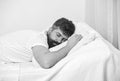 Man in shirt laying on bed, white wall on background. Guy on calm face sleeping on white sheets and pillow. Macho with Royalty Free Stock Photo