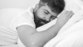 Man in shirt laying on bed, white wall on background. Macho with beard and mustache sleeping, relaxing, having nap, rest Royalty Free Stock Photo