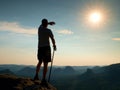 Man in shirt and pants on cliff of sandstone rock in national park Saxony Switzerland and watching over the misty and foggy morni Royalty Free Stock Photo