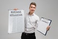 Young man holding poster with mortgage application and contract isolated on light background