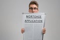 Young man keeps in front of him poster with mortgage application isolated on light background