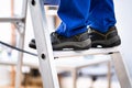 Man In Shoes Climbing Step Ladder. Safety Royalty Free Stock Photo