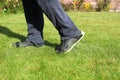 A man in shoes with spikes for aerating the lawn. Garden care