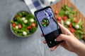 Man shooting fresh vegetable salad with mozzarella and spinach on cell phone camera. Cooking, blogging and healthy Royalty Free Stock Photo