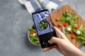 Man shooting fresh vegetable salad with mozzarella and spinach on cell phone camera. Cooking, blogging and healthy Royalty Free Stock Photo