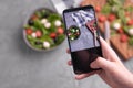 Man shooting fresh vegetable salad with mozzarella and spinach on cell phone camera. Cooking, blogging and healthy Royalty Free Stock Photo