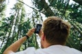 Man shoots trees and sky in the forest on a smartphone camera on a hike. Guy makes photo content in the mountain forest for social
