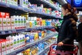 Minsk, Belarus, March 25, 2018: Man shopping milk in grocery store. Young woman reading ingredients,declaration or expiration date