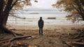 A man on the shore of a lake or the sea looks longingly into the distance