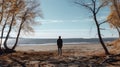 A man on the shore of a lake or the sea looks longingly into the distance