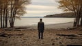 A man on the shore of a lake or the sea looks longingly into the distance