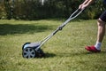 Man in shorts mowing green lawn with a cylinder mower Royalty Free Stock Photo