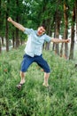 A man in shorts and a shirt is joyful jumping on the grass