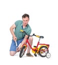 Man in shorts and a t-shirt pumping wheel at children`s bike. Isolated on white background.