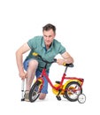 Man in shorts and a t-shirt pumping wheel at children`s bike. Isolated on white background.