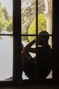 Man in shorts and tee shirt sitting in window looking at cell phone- unrecognizable almost silhouette Royalty Free Stock Photo